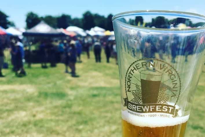 Glass of beer showing Northern Virginia Brewfest logo and crowd in the background. 